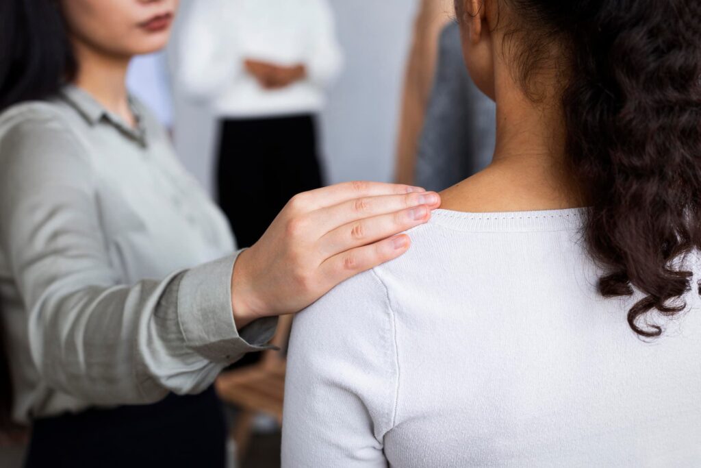 A woman is adjusting the back of another woman's shirt.