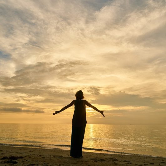yoga-woman-beach Woman on a beach facing the sunset.